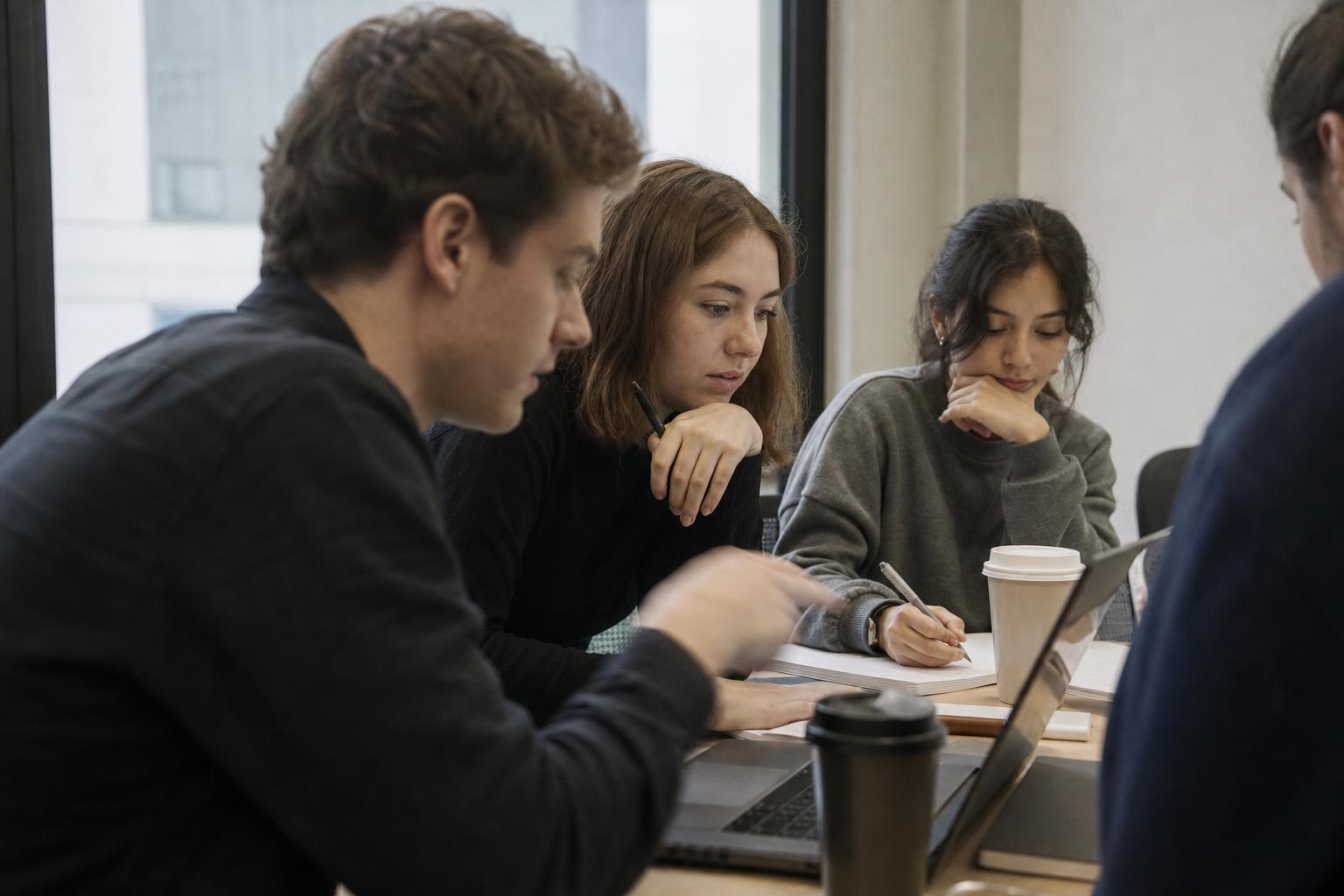 A small talent team reviewing project notes around a laptop in a bright meeting room